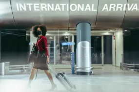 Businesswoman with face mask walking through airport terminal